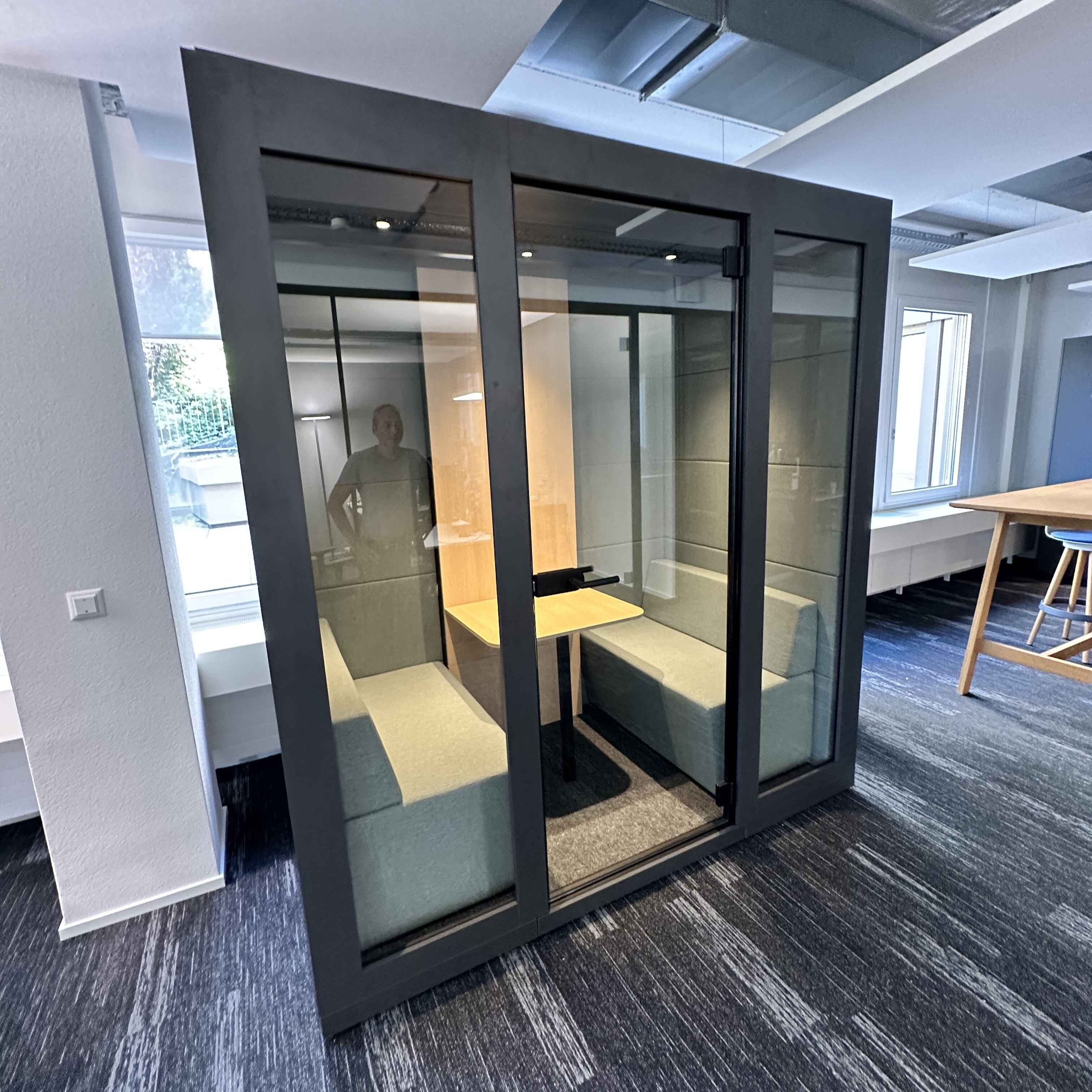 Besprechungsbox Silent Room M mit hellen Sitzbaenken, Glastueren und Holzverkleidung – akustisch abgeschirmter Raum fuer ruhige Teammeetings und kreative Zusammenarbeit im Buero