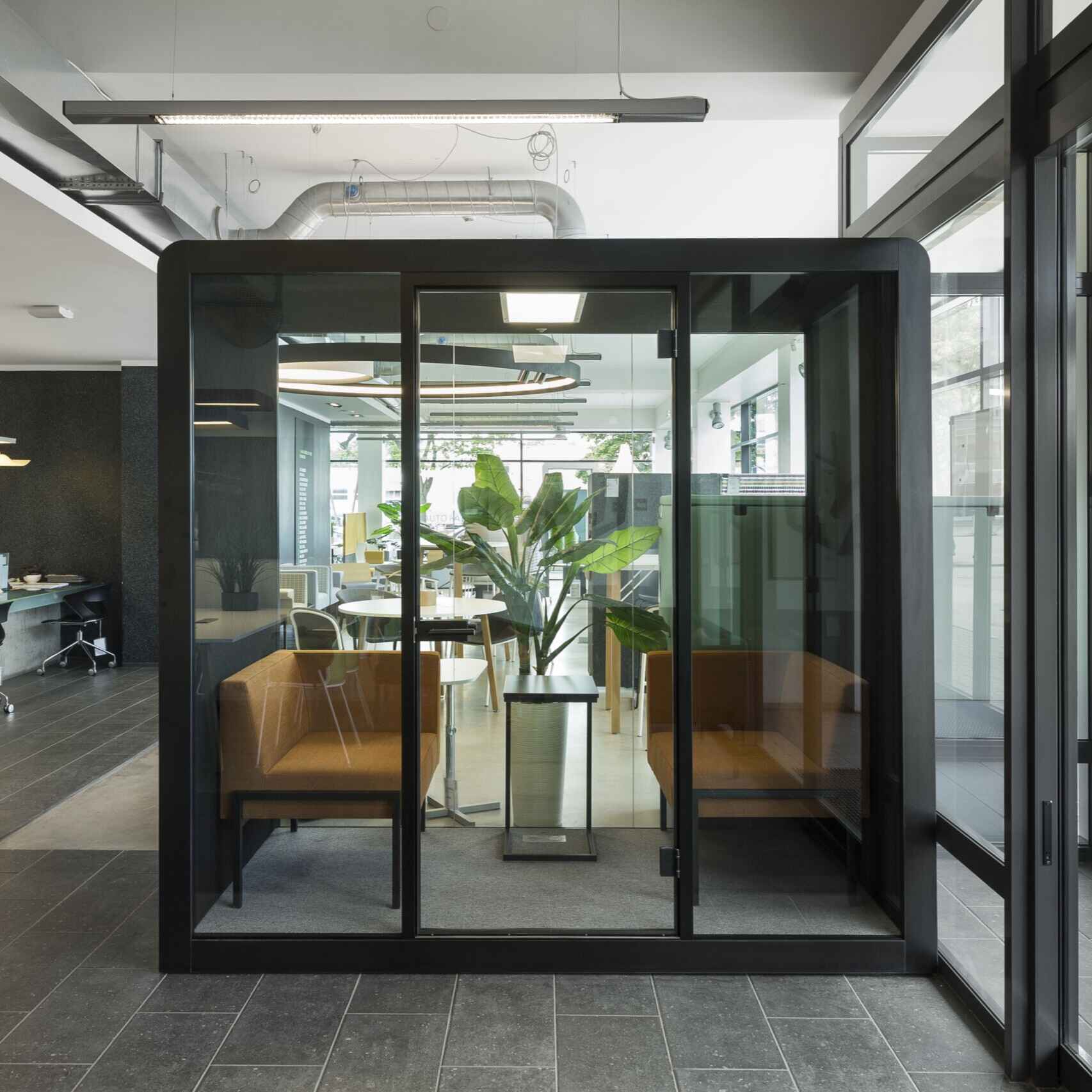 Innenansicht der Silen Space Buerobox mit grossem Tisch, gepolsterten Sitzen und LED-Beleuchtung – komfortable Arbeitsumgebung fuer Besprechungen und Teamarbeit im Buero