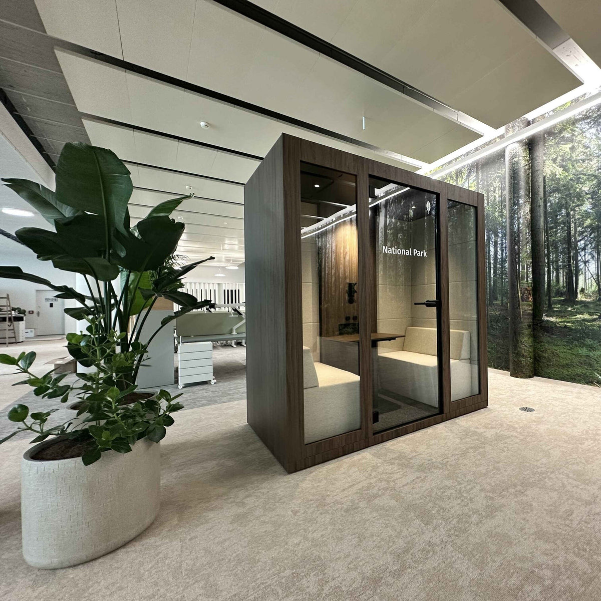 Besprechungsbox Silent Room M mit zwei Personen im Gespraech – akustisch abgeschirmte Kabine mit gepolsterten Sitzbaenken und Tisch fuer effiziente Teammeetings im Buero