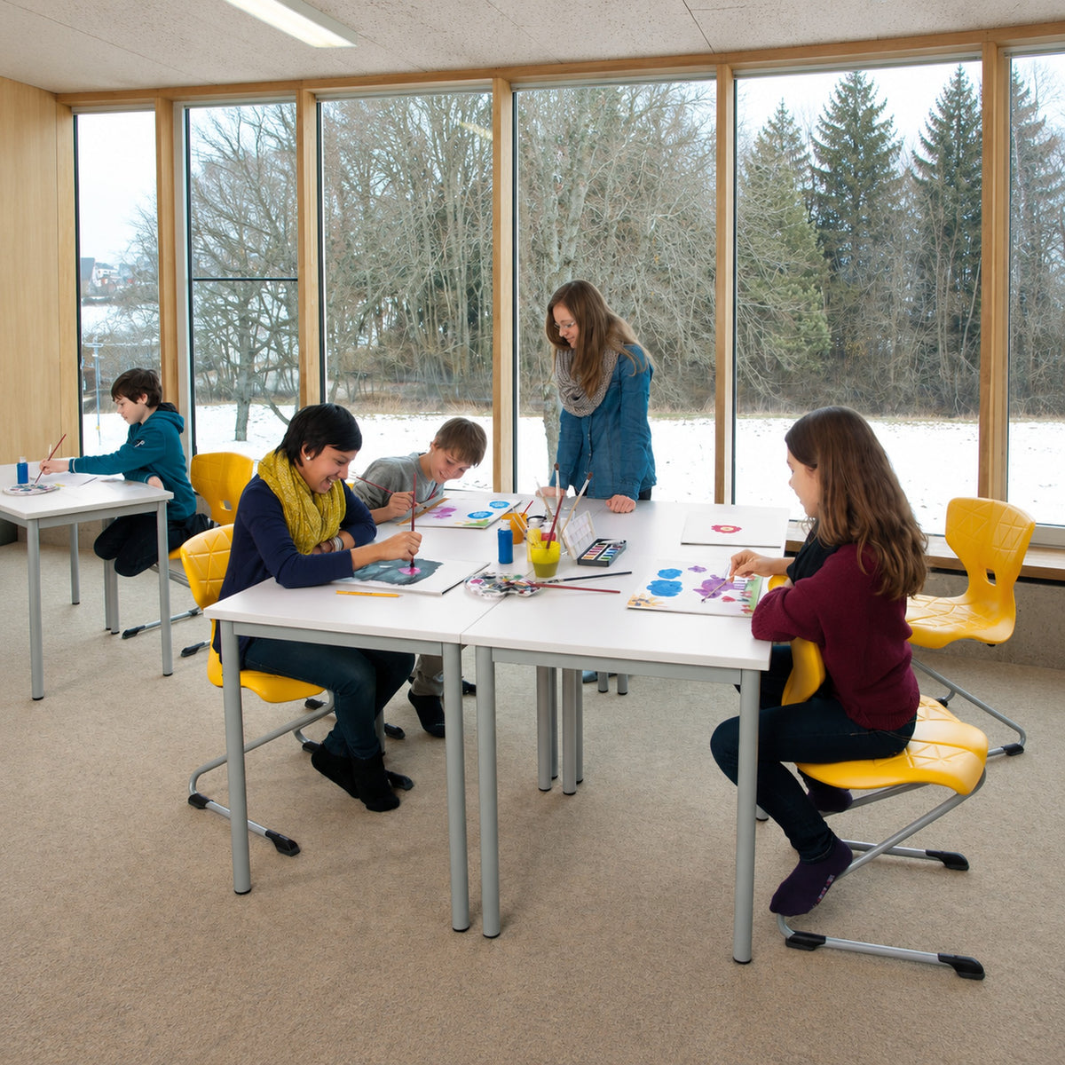 Schultisch 2er mitwachsend höhenverstellbar für Schule & Seminar beim Malen im hellen Schulraum mit gelben Stühlen.