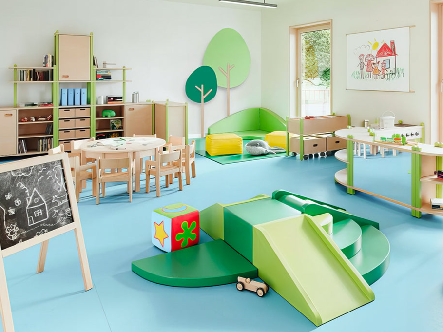 Kindergartenraum mit kindgerechten Moebeln und einer Spielburg aus Holz, kombiniert mit farbenfrohen Stuehlen, Tischen und Regalen, gestaltet fuer kreatives Spiel und Lernen, praesentiert von Kibemo