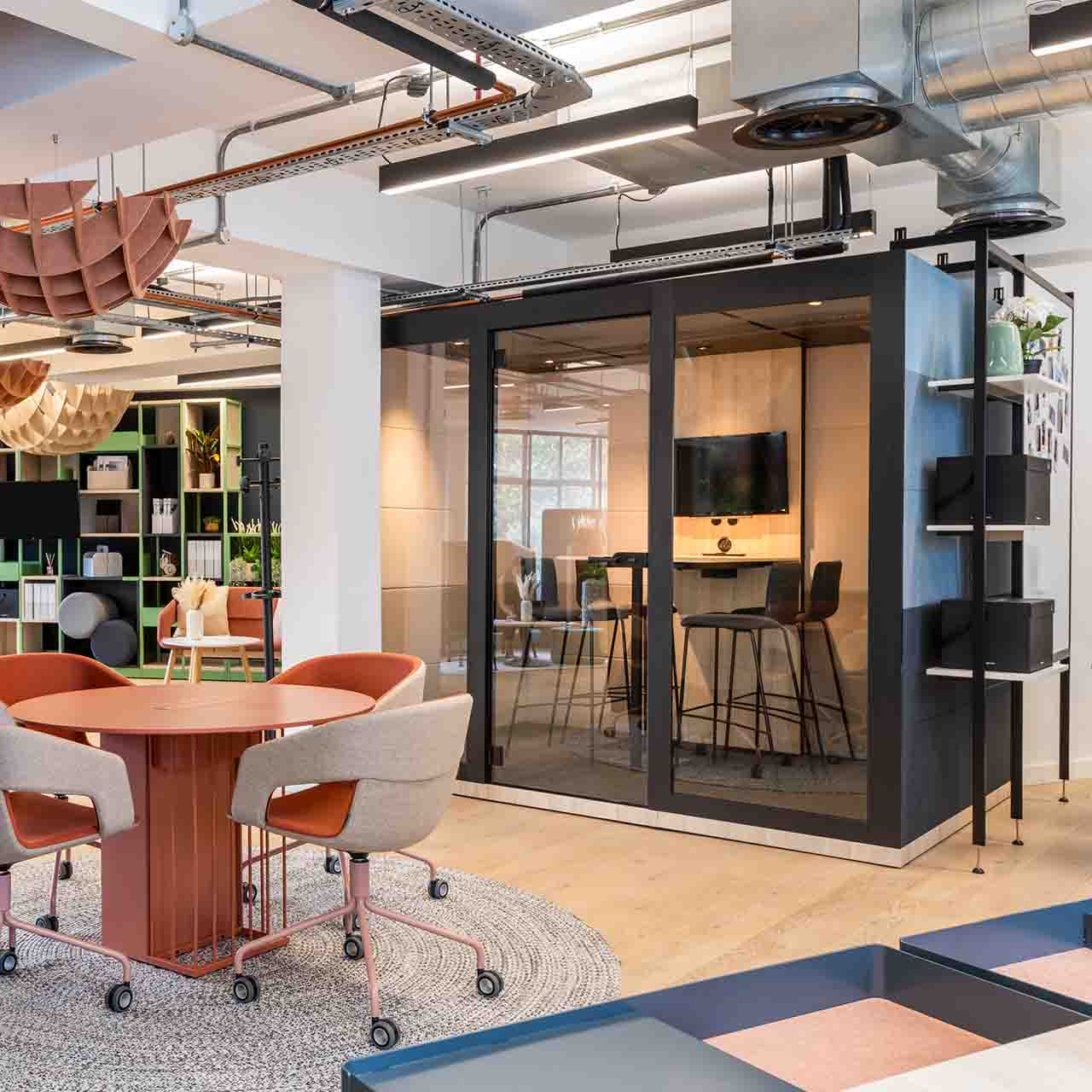 Silent Room L Meetingbox in modernem Buero mit Glasfront, integriertem Bildschirm und Barhockern – stilvolle Raum-in-Raum Loesung fuer hybride Besprechungen und kreative Teamarbeit