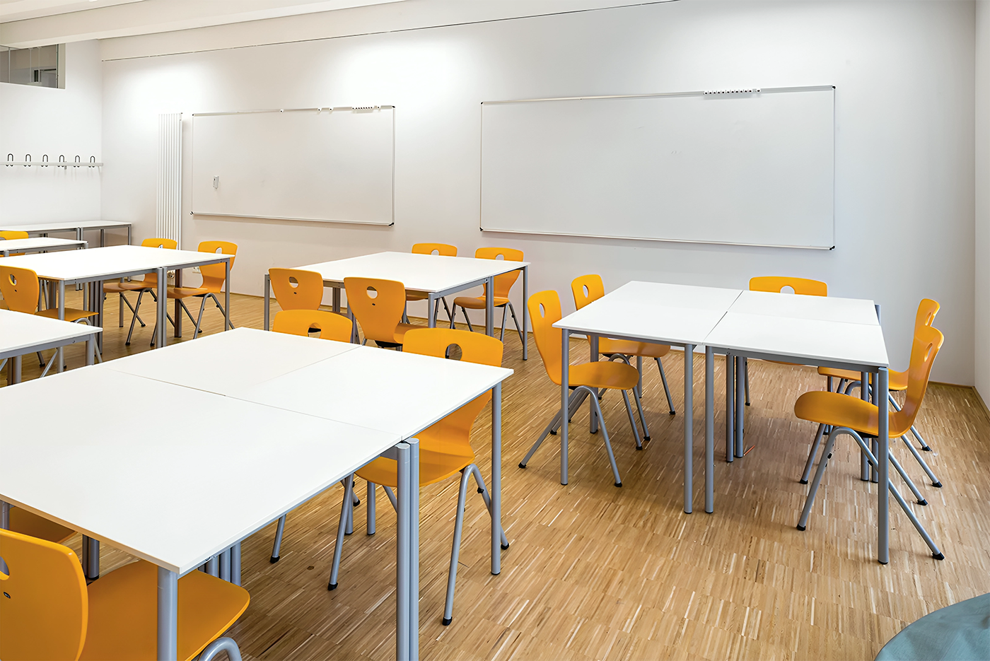 Moderne Klassenzimmer-Einrichtung mit weißen Tischen und leuchtend gelben Stuehlen, ideal für eine produktive und einladende Lernumgebung.