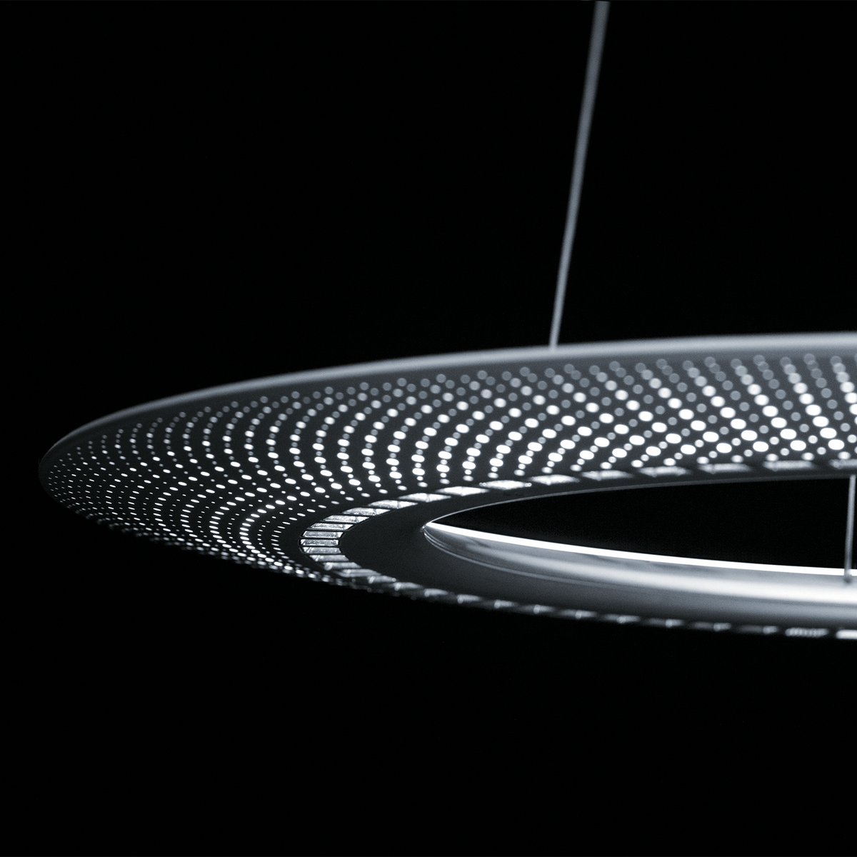 Detail der Zumtobel AMBITUS Pendelleuchte mit perforiertem Leuchtenring und innenliegender Reflektoroptik.